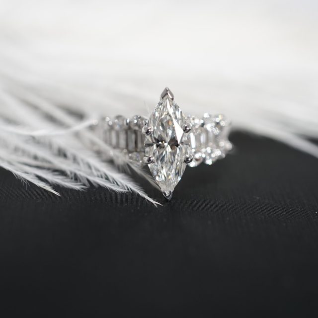 Marquise diamond ring with baguette and pear side stones on a white feather