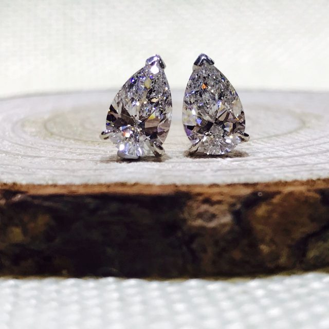 Pear-shaped diamond stud earrings on a slice of wood