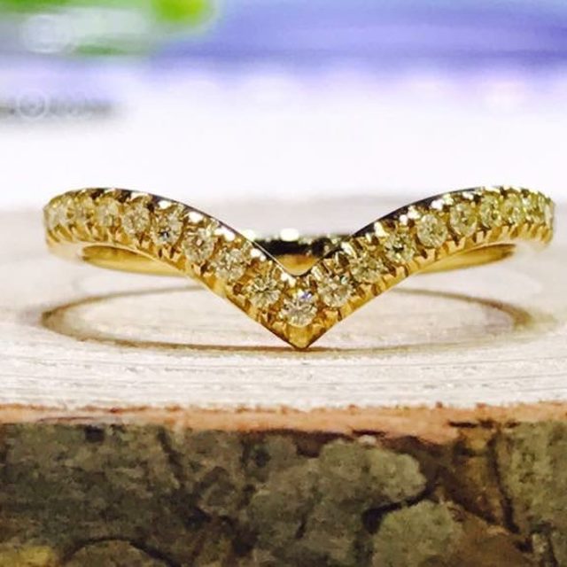 Yellow gold V-shaped diamond band on a wood slice