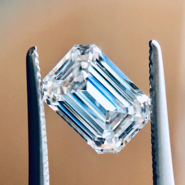 Emerald-cut loose diamond held in tweezers