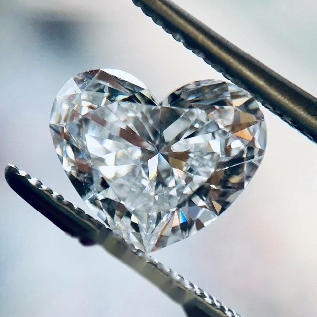 Heart-shaped loose diamond held in tweezers