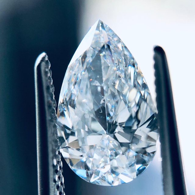 Pear-shaped loose diamond held in tweezers