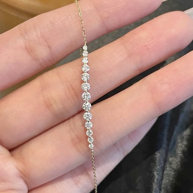Delicate chain bracelet with a row of graduated round diamonds, held in a hand