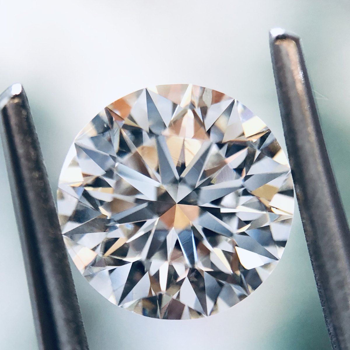 A round brilliant diamond held in tweezers, its facets catching the light